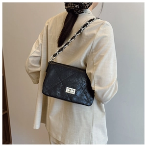 Close-up of quilted leather crossbody bag with silver chain strap and metal turn-lock