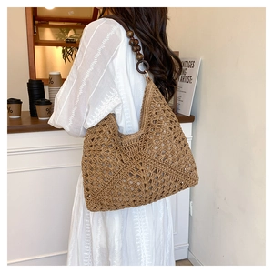 Detail of woven straw bag featuring hollow crochet pattern and brown wooden bead strap