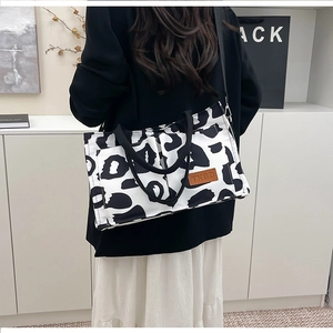 Detail of cow print tote bag with brown leather label and adjustable strap