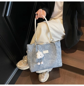 Détail du sac cabas en toile florale avec bandoulières en cuir blanc et charm nuage