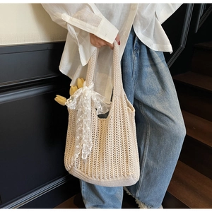 Detail of beige crochet tote bag featuring vertical hollow texture and white lace bow