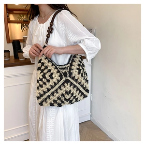 Detail of hollow-out straw shoulder bag with wooden bead strap and bohemian texture