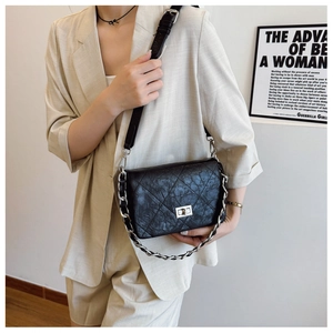 Close-up of quilted black leather texture and silver metal twist-lock on the chain bag
