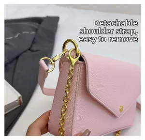 Detail of pink pebbled leather bag featuring a detachable strap with gold metal hook