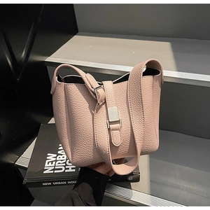 Détail macro du cuir grainé rose et de la boucle argentée sur le sac seau