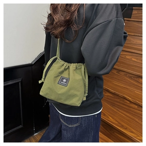 Close-up of military green drawstring bucket bag with black logo patch and nylon texture