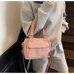 Detail of pink nylon crossbody bag with adjustable strap worn by model in casual style