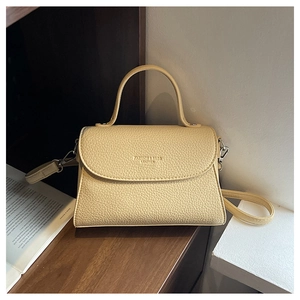 Détail du sac trapèze en cuir beige grainé avec finitions métalliques argentées et poignée