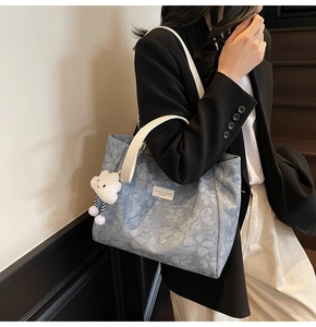 Détail du sac cabas fleuri bleu avec pendentif nuage et logo métallique frontal