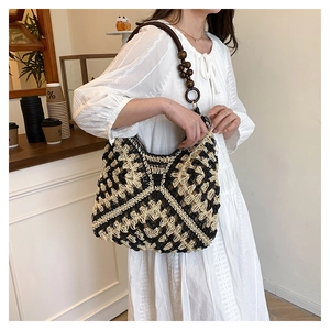 Detail of hand-woven straw shoulder bag featuring dark brown wooden beads and rings