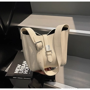 Gros plan du sac seau en cuir crème avec boucles argentées et grainage de qualité