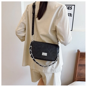 Close-up of black quilted crossbody bag with silver rotating lock and metal chain strap