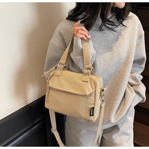 Détail du sac à main en nylon kaki avec grand rabat et étiquette porté par un mannequin