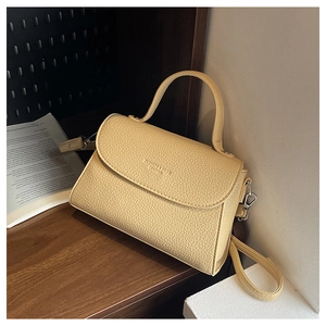 Vue détaillée de la texture du cuir grainé et du logo sur le petit sac beige clair