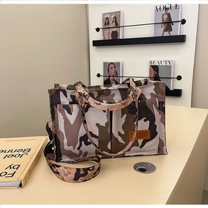 Detail of camouflage tote bag with leather logo tag and adjustable wide shoulder strap