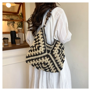 Detail of contrast crochet straw shoulder bag with wooden bead straps and geometric texture