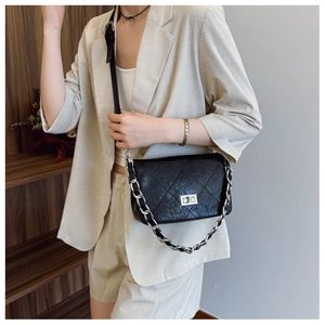 Detailed shot of a black quilted crossbody bag with silver chain strap and metal turn lock