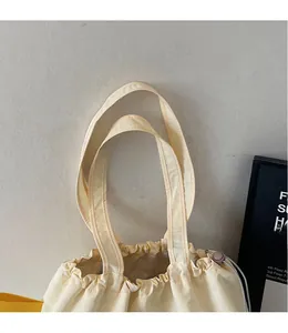 Detail of smooth long shoulder straps and drawstring closure on a beige tote bag