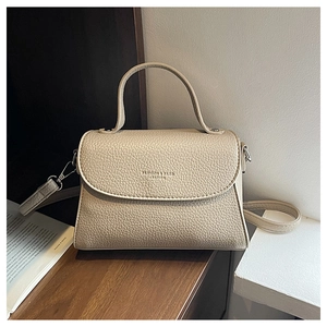 Détail du sac à bandoulière en cuir beige grainé avec finitions métalliques et logo