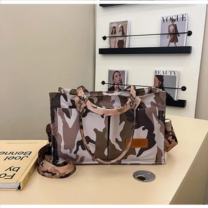Detail of camouflaged canvas tote bag featuring brown leather ZXBD logo and side pocket
