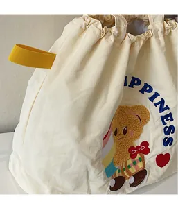 Detail of drawstring tote bag with embroidered teddy bear and blue happiness text