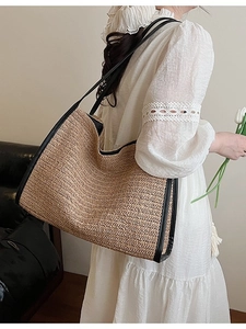 Large woven straw tote bag with black leather trim and long shoulder straps for women
