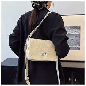 Close-up of beige quilted crossbody bag with silver chain strap and metal turn-lock