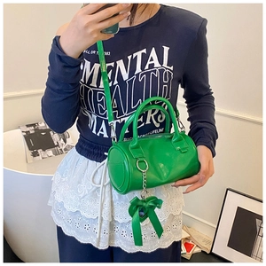 Close-up of bright green cylinder handbag with ribbon bow and detachable shoulder strap