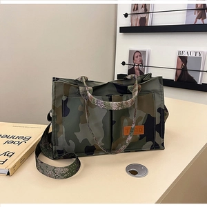 Detail of camouflage tote bag with reinforced handles and brown leather logo patch