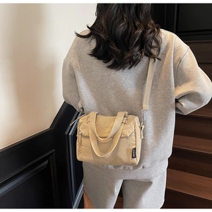 Sac à bandoulière chic en toile beige avec poignées, vue de dos dans un style élégant