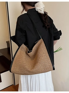 Large straw woven tote bag with black leather straps and trim for beach or commute