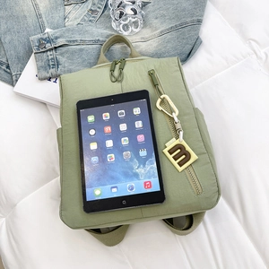Detail of light green waterproof backpack with dual zippers and square trendy pendant