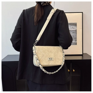 Detail of beige quilted leather crossbody bag with metal twist lock and gold chain strap
