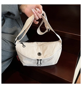 Detail of off-white nylon crescent crossbody bag with red side label and zippers