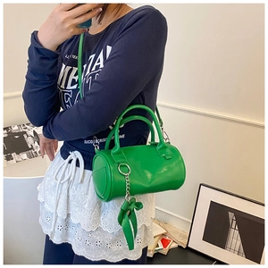 Dettaglio borsa a cilindro verde con catena metallica e decorazione in foulard di seta