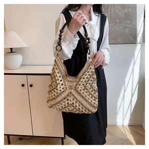 Detail of bohemian straw bag featuring hollow floral pattern and wooden bead handle