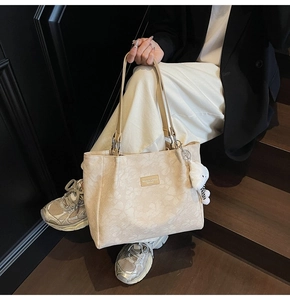 Détail du sac cabas beige à motif floral avec étiquette en cuir et lapin en peluche
