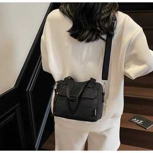 Détail du sac bandoulière en toile noire avec bandoulière réglable et boucle en métal