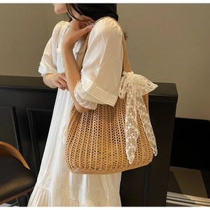 Detail of woven straw tote bag featuring a large white lace crochet bow on the side