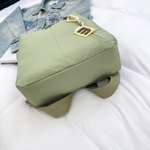 Detail of light green nylon backpack featuring a trendy yellow Extreme tag and soft texture