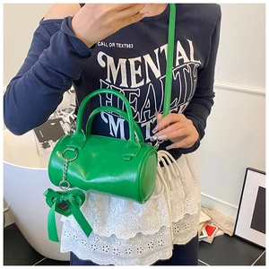 Dettaglio mini borsa a cilindro verde con ciondolo a cuore e tracolla sottile