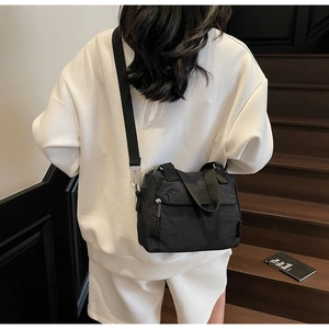 Vue de dos d'un sac seau en nylon noir avec une large bandoulière en situation réelle
