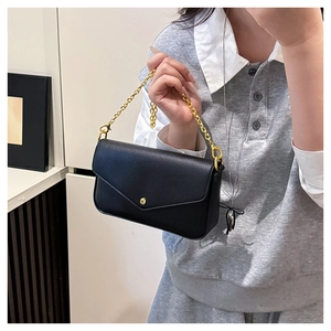 Close-up of black lychee grain leather crossbody bag with elegant gold chain and round buckle