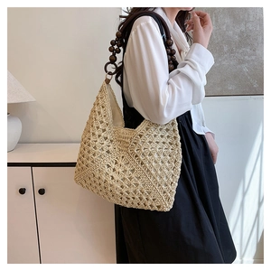 Close-up of woven straw tote bag featuring hollow patterns and dark wood bead handles