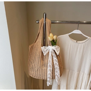 Detail of beige knit tote bag with intricate crochet patterns and a lace bow decoration