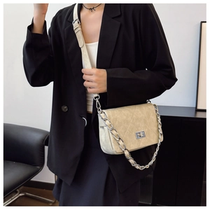 Close-up of beige quilted crossbody bag with silver twist lock and chain strap detail