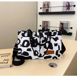 Detailed view of large cow print tote bag with adjustable strap and logo patch