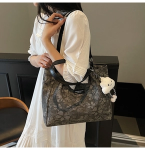 Close-up of large tote bag with floral pattern and plush white cloud charm decoration