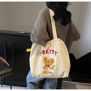 Detail of cute bear embroidery and red PRETTY lettering on off-white canvas tote bag