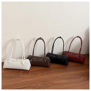 Four minimalist baguette bags in white, brown, black, and dark red on a wooden floor